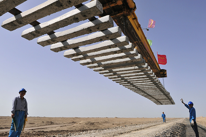 Workers direct a crane to lay a segment of tracks on the Kumul-Lop Nor line's railway bed in Lop Nor, Xinjiang Uighur Autonomous Region July 15, 2012. (Reuters / Rooney Chen)