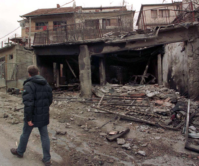A man passes destroyed houses in Pristina as NATO air strikes continue March 29, 1999. (Reuters)